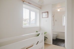 Een badkamer met een douche, toilet en een raam met zonwering.