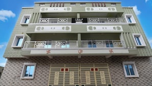 A multi-story building with balconies, a company-serviced sign, and a decorative entrance gate. - Collection O Shree Jagannatha Temple (Puri)