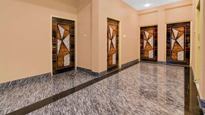 A hallway with three doors, each with a geometric pattern, leading to rooms. The floor is tiled with a marble-like pattern. - Collection O Shree Jagannatha Temple (Puri)