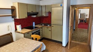 Eine kleine Küche mit Kühlschrank, Herd, Spüle und Holzschränken.