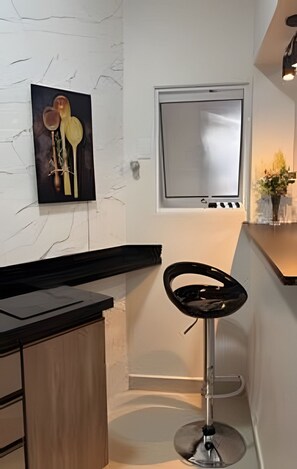 Una cocina moderna con salpicadero de mármol, encimera negra y una zona de bar con un taburete.