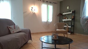 Uma sala de estar com sofá, poltrona, mesa redonda e estante.