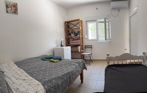 Een slaapkamer met twee bedden, een bureau met lamp, een stoel, een kledingkast en een raam.