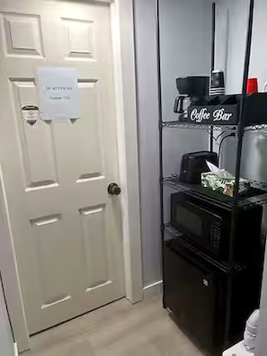 A door with a 'DO NOT DISTURB' sign and a 'Coffee Bar' sign above a shelf with a coffee maker and a box. - Cozy European Studio Walk to Caesars Free Parking (Windsor)