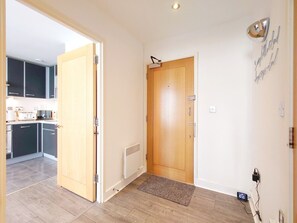 Ein Flur, der zu einer Küche mit einer Holztür und einem Heizkörper führt.