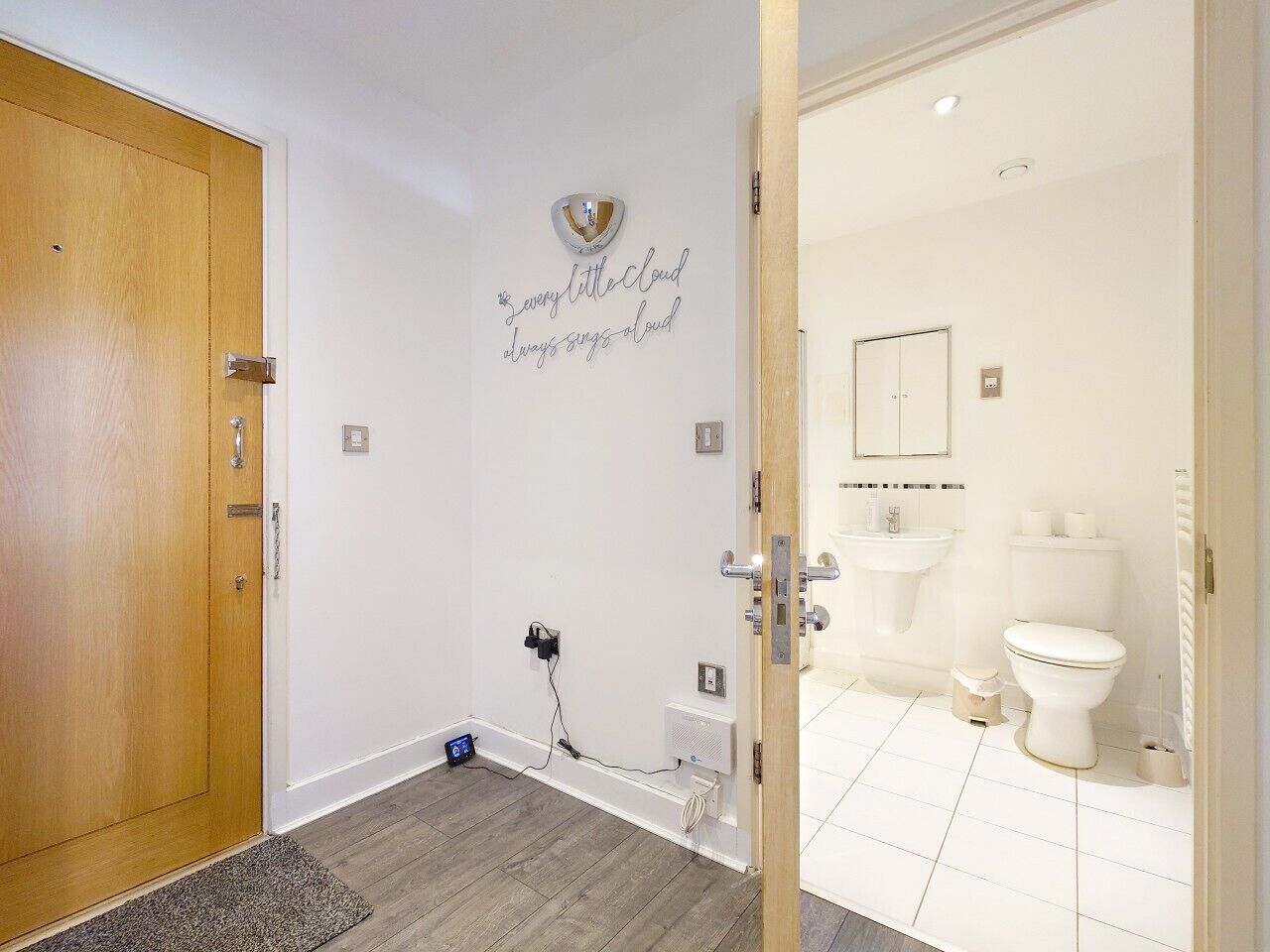 A bathroom with a toilet, sink, and a wall-mounted mirror.