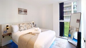 Camera d'albergo con un letto grande, un comodino con una lampada, uno specchio e vista su un balcone.