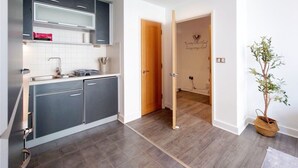 Una cucina moderna con mobili grigi, un piano di lavoro bianco e una porta in legno che dà su un'altra stanza.