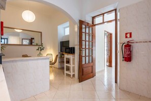 A modern kitchen with a marble countertop, a wooden-framed door, and a fire extinguisher on the wall. - Casa da Bica T2 250m Old Town Beach (Albufeira)