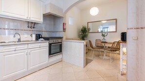 Eine moderne Küche mit weißen Schränken, einem eingebauten Backofen und einem Essbereich mit Tisch und Stühlen.