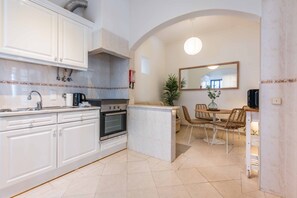 Eine moderne Küche mit weißen Schränken, einem eingebauten Backofen und einem Essbereich mit Tisch und Stühlen.