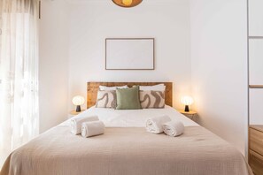 A neatly made bed with two pillows, two bedside lamps, and a framed picture on the wall. - Casa da Bica T2 250m Old Town Beach (Albufeira)
