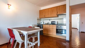 A compact kitchen with wooden cabinets, a microwave, and a built-in oven. - Apartamento T1 Vistamar Centro Hist Rico Albufeira (Albufeira)