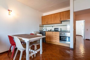 A compact kitchen with wooden cabinets, a microwave, and a built-in oven. - Apartamento T1 Vistamar Centro Hist Rico Albufeira (Albufeira)