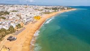An aerial view of a coastal city with a sandy beach, a marina, and buildings along the shore. - Apartamento T1 Vistamar Centro Hist Rico Albufeira (Albufeira)
