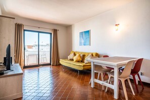 A living room with a sofa, a dining table, and a TV. - Apartamento T1 Vistamar Centro Hist Rico Albufeira (Albufeira)