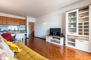 A living room with a sofa, a television, and a dining area with chairs and a table. - Apartamento T1 Vistamar Centro Hist Rico Albufeira (Albufeira)
