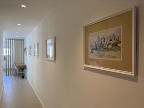 A hallway with framed artwork on the walls, a dining area with a table and chairs, and a view into another room. - Central Town Classy T2 by Agarve Lodging (Albufeira)