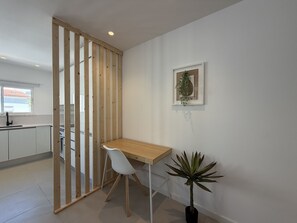 A modern kitchen with white cabinets, a wooden partition, a dining table with a white chair, and a potted plant. - Central Town 2-bedroom Classy Apartment Albufeira (Albufeira)