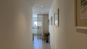 A hallway with a wooden partition, a dining area with a table and chairs, and framed pictures on the walls. - Central Town 2-bedroom Classy Apartment Albufeira (Albufeira)