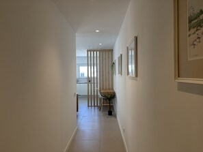 A hallway with a wooden partition, a dining area with a table and chairs, and framed pictures on the walls. - Central Town 2-bedroom Classy Apartment Albufeira (Albufeira)