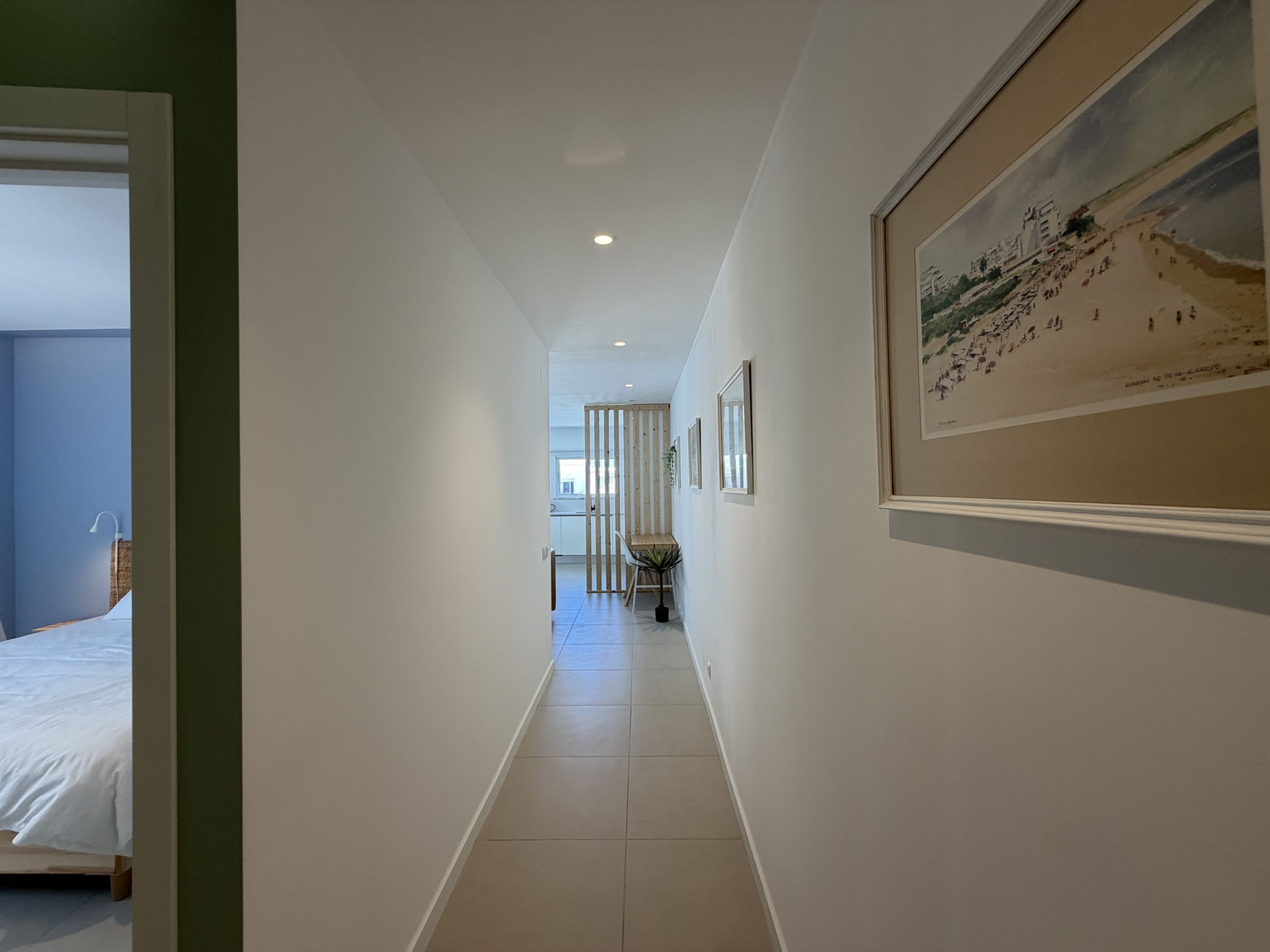 Een hal met een bed, een eethoek en een gekaderd schilderij aan de muur.