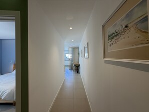 A hallway with a bed, a dining area, and a framed painting on the wall. - Central Town 2-bedroom Classy Apartment Albufeira (Albufeira)
