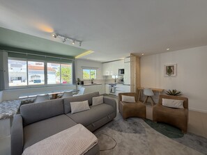 A modern living room with a sofa, chairs, a coffee table, and a view of the kitchen. - Central Town 2-bedroom Classy Apartment Albufeira (Albufeira)