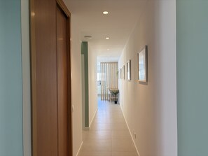 A hallway with a wooden door, a plant, and framed pictures on the wall. - Central Town 2-bedroom Classy Apartment Albufeira (Albufeira)
