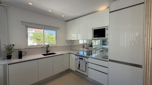 A modern kitchen with white cabinets, a built-in oven, and a window with a view of trees. - Central Town 2-bedroom Classy Apartment Albufeira (Albufeira)