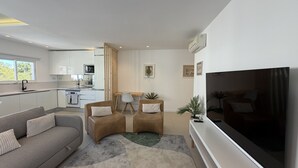 A modern living room with a sofa, two armchairs, a coffee table, a flat-screen TV, and a kitchen in the background. - Central Town 2-bedroom Classy Apartment Albufeira (Albufeira)