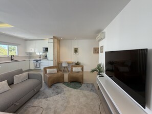 A modern living room with a sofa, two armchairs, a coffee table, a flat-screen TV, and a kitchen in the background. - Central Town 2-bedroom Classy Apartment Albufeira (Albufeira)