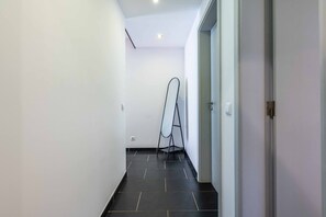 A narrow hallway with a black tiled floor, white walls, and a door on the right. - Geneve Old Town T3 Apartment (Albufeira)