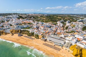 Eine Küstenstadt mit Strand, Gebäuden und einer felsigen Klippe.