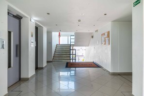 A clean, modern hotel lobby with a staircase, a reception desk, and a bulletin board. - Old Town Bayview T1 w Pool - 350m to Beach (Albufeira)