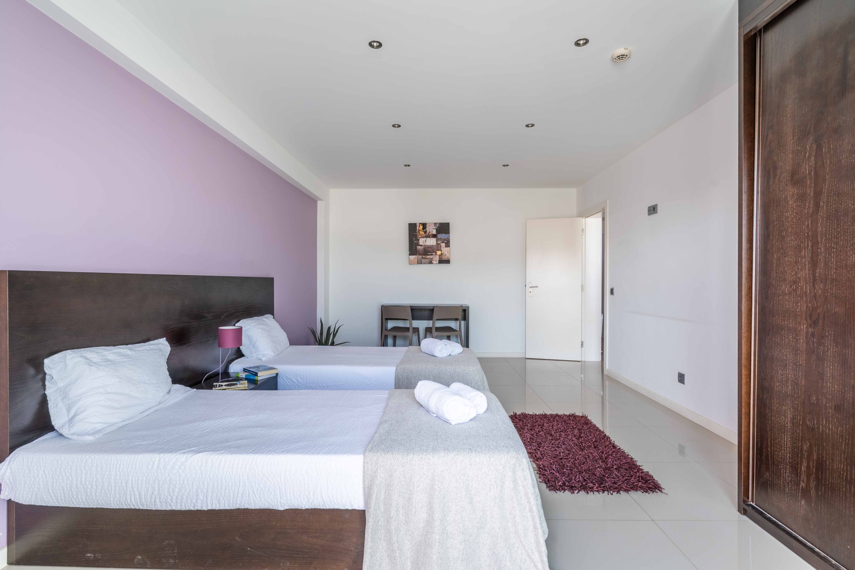 Une chambre d’hôtel moderne avec deux lits, un bureau et un grand miroir.