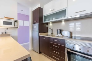 Eine moderne Küche mit Mikrowelle, Kühlschrank, Herd und Spüle mit Wasserkocher.