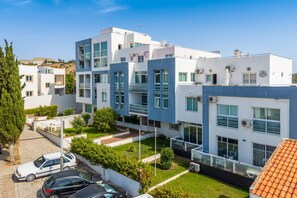 Ein modernes Mehrfamilienhaus mit Balkonen, einer gepflasterten Auffahrt und geparkten Autos.