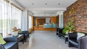 Um saguão de hotel com balcão de recepção, área de estar e parede de pedra.