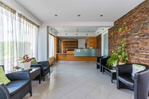 Eine Hotelhalle mit Rezeption, Sitzgelegenheiten und einer Steinwand.