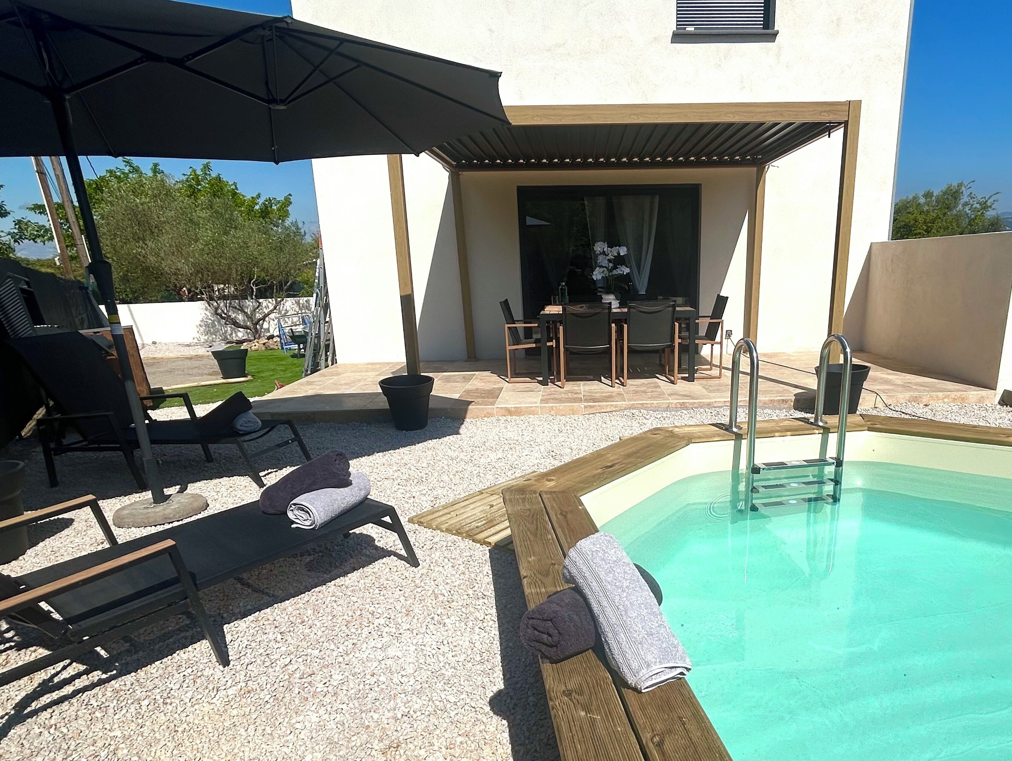 A poolside area with a sun lounger, a table, and a grill.