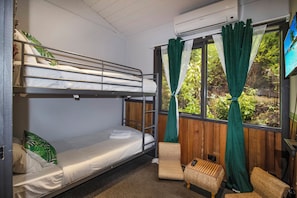 Une chambre avec un lit superposé, une fenêtre, une chaise et une petite table.