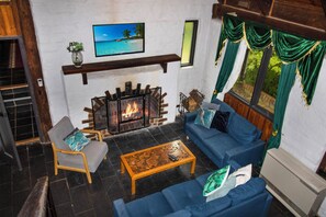 Ein Wohnzimmer mit Kamin, einer Couch, einem Sessel und einem Couchtisch.