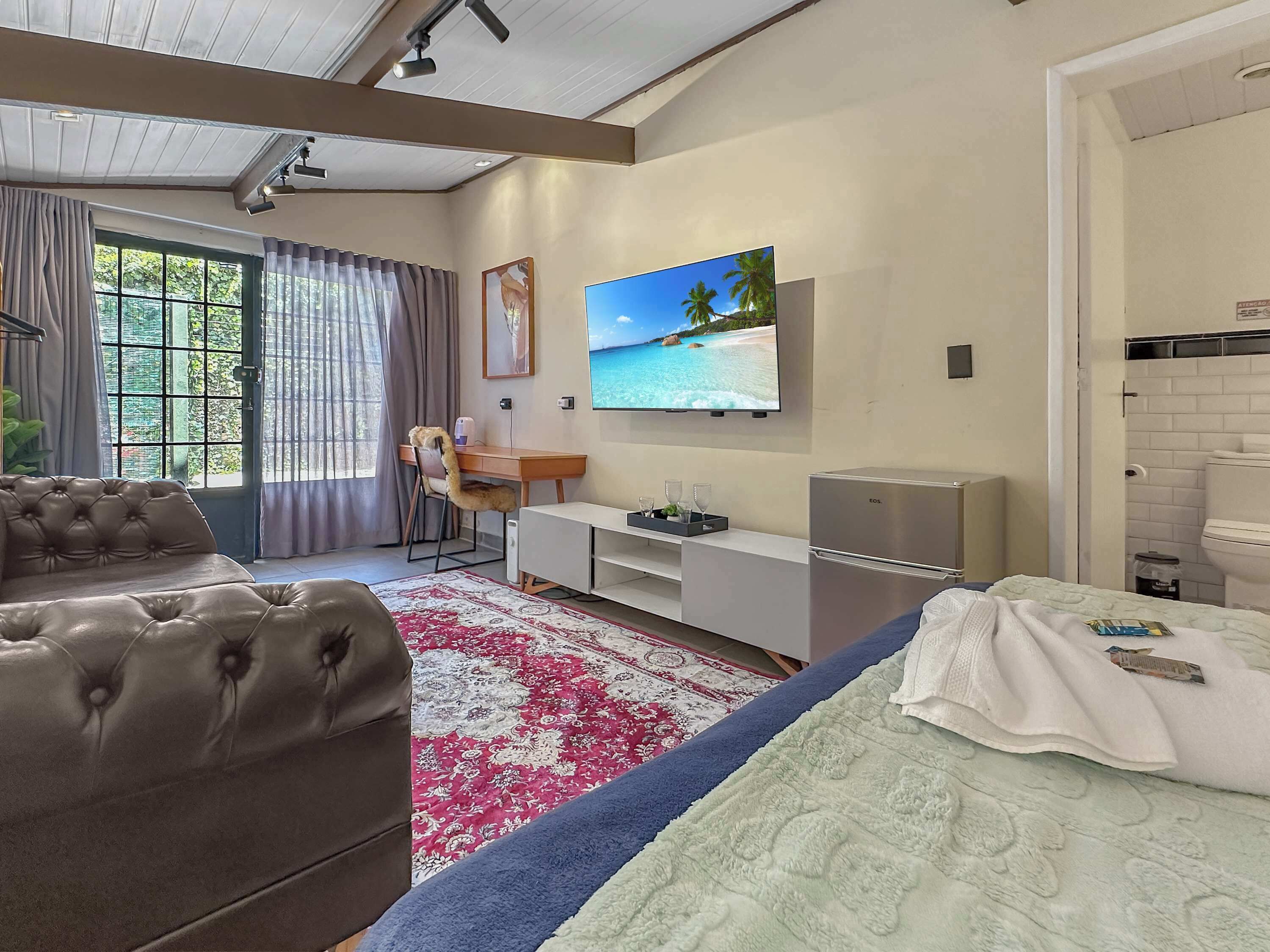 Ein Hotelzimmer mit Bett, einer Couch, einem Schreibtisch, einem Fernseher und einer Minibar.