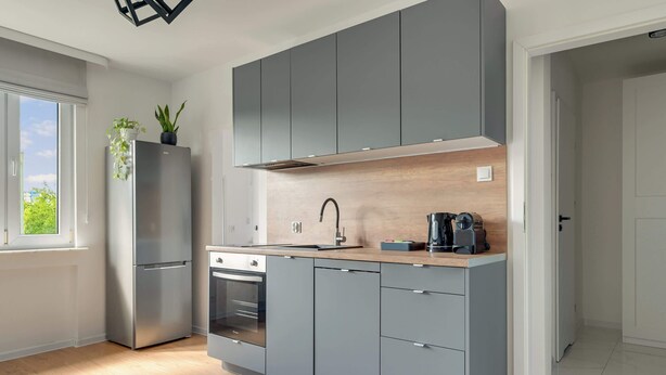 Una cocina moderna con armarios grises, un refrigerador de acero inoxidable y un horno empotrado.