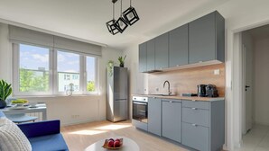 Cocina moderna con gabinetes grises, un refrigerador de acero inoxidable y un horno empotrado.