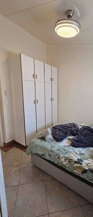 A bedroom with a bed, a wardrobe, and a ceiling light. - Aloe Self Catering Two Bedroom Apartment Open Plan (Port Shepstone)