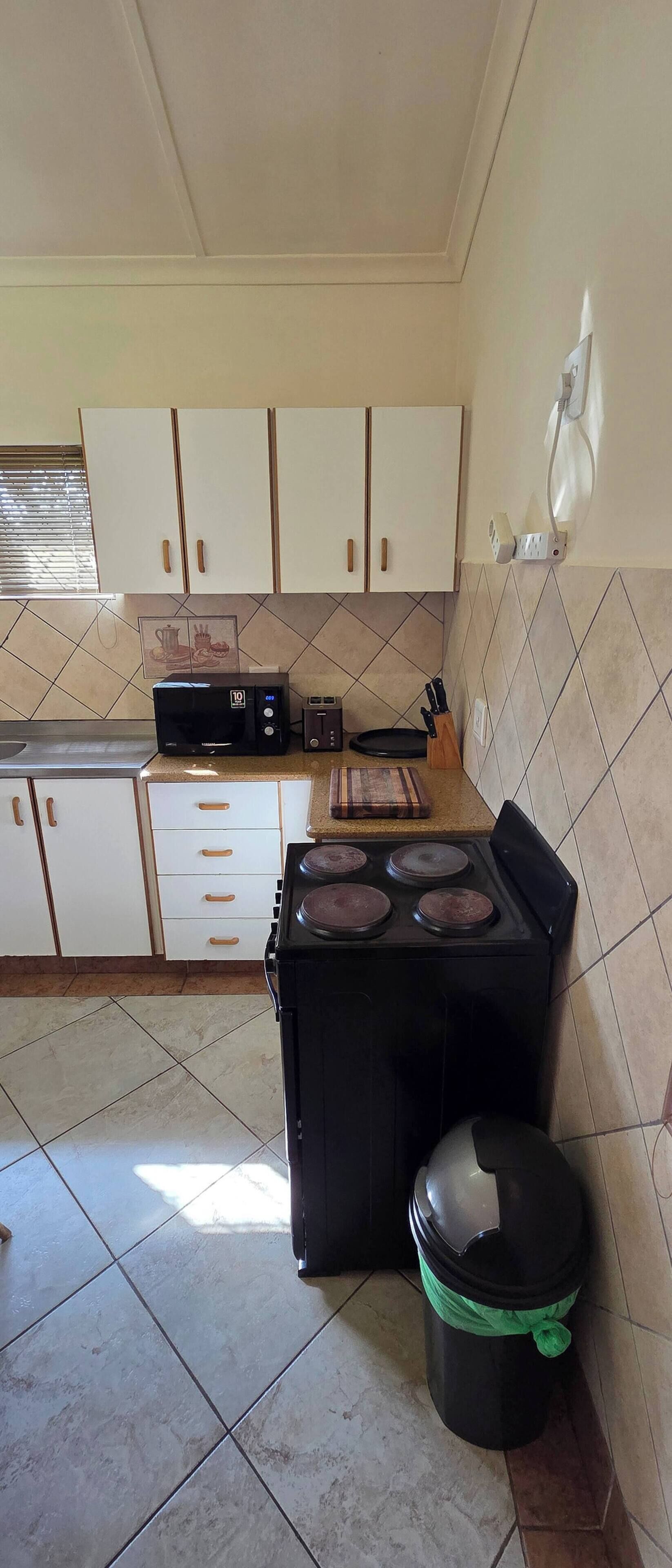 Una cocina con armarios blancos, microondas, tostadora y cocina a gas.