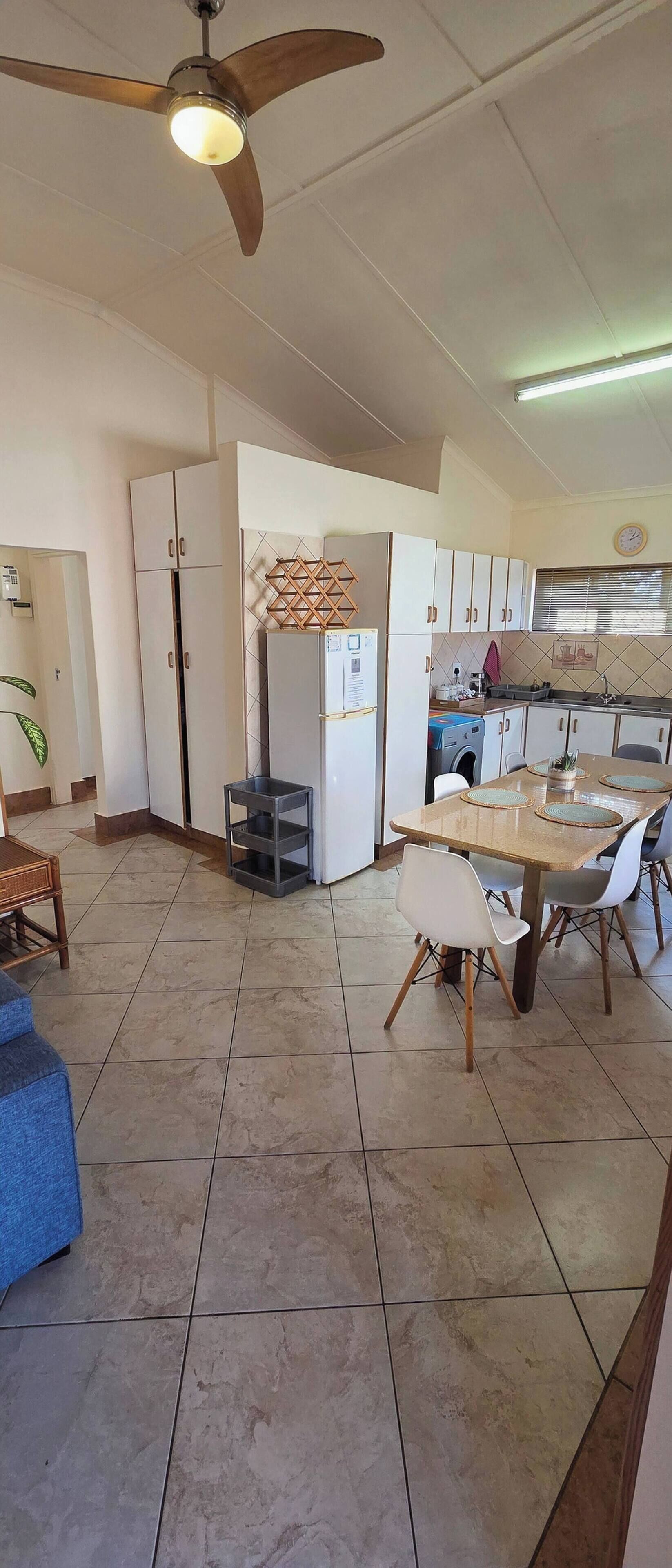 A spacious kitchen with a dining area, a ceiling fan, and a refrigerator.