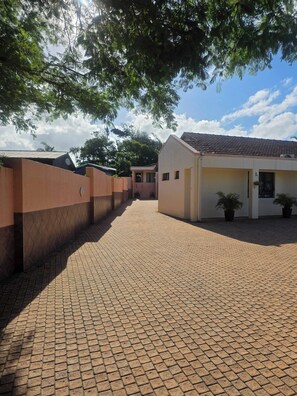 Un patio empedrado con un edificio de techo a ladrillo y una pared con diseño de rombos.